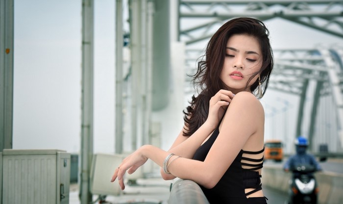 Woman with long hair wearing a black dress on a bridge
