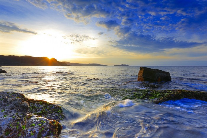 Sunset over the sea with rocks and waves