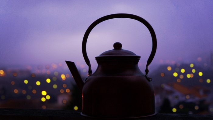 Silhouette of a copper teapot against a bokeh background
