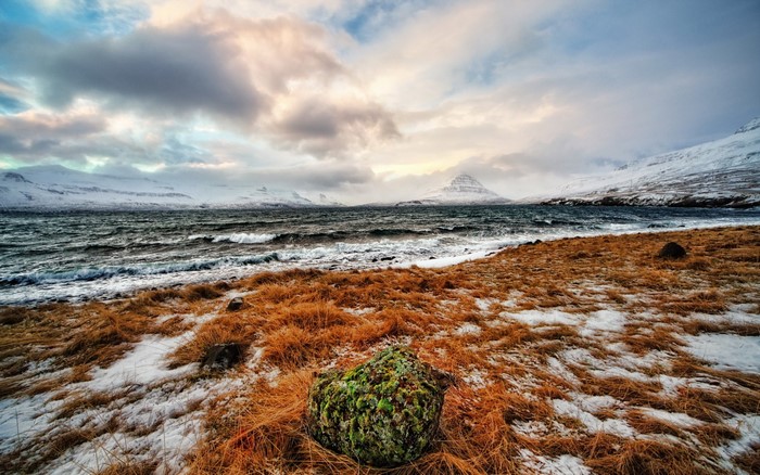 Winter landscape with snow-covered mountains and a rough sea