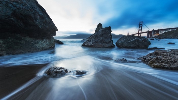 Golden Gate Bridge and rocky shore with long exposure water
