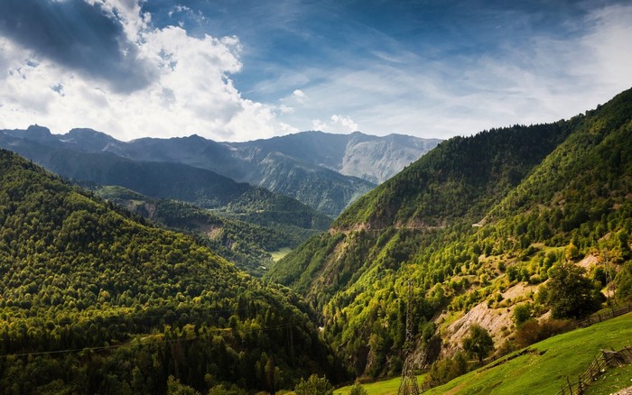 Green forested mountains and valley under a cloudy sky
