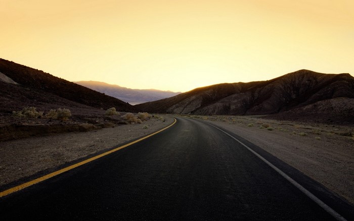 Desert road at sunset with mountains