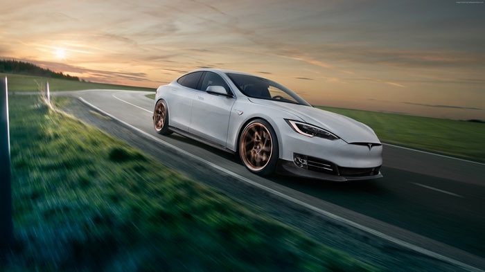 White Tesla Model S driving on a road at sunset
