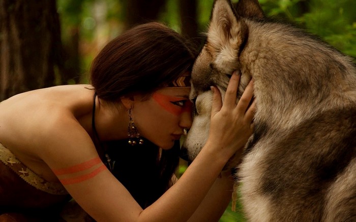 Woman with face paint and wolf in forest