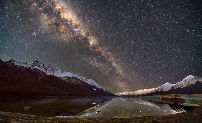 Milky Way over snow-capped mountains and a lake