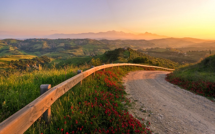 Winding dirt road through rolling hills at sunset