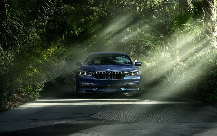 Blue BMW Alpina B7 driving through a forest