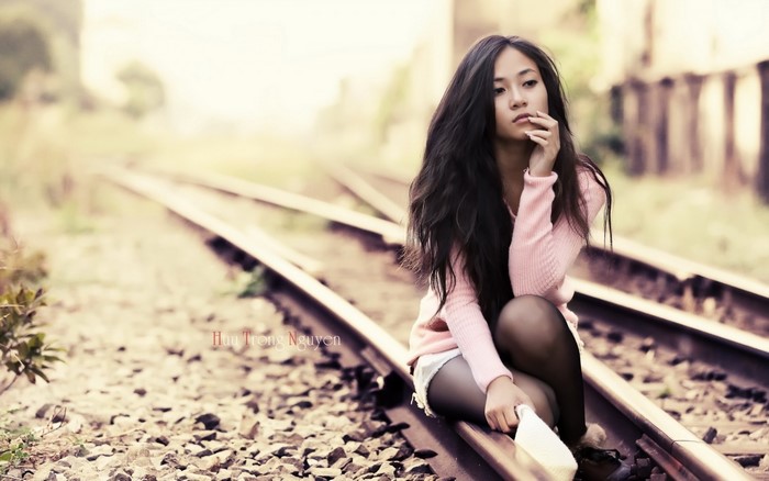 Thoughtful Woman Sitting on Train Tracks in Soft Light