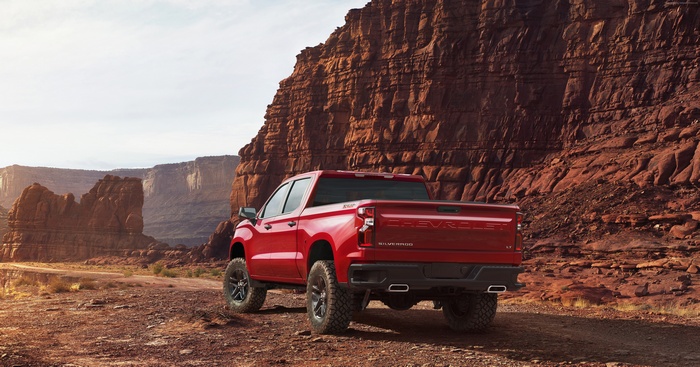 Red Chevrolet Silverado truck in desert landscape