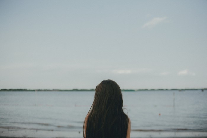 Woman with long hair looking at the sea