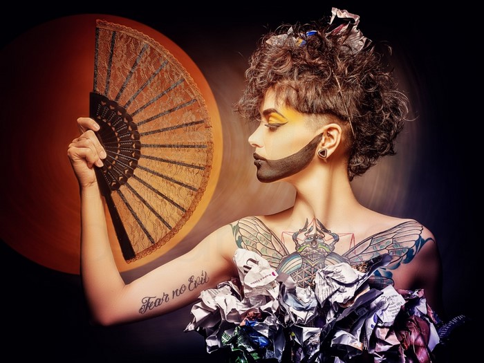 Woman with elaborate makeup and costume holding a fan