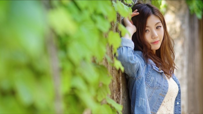 Asian woman with long brown hair in denim jacket