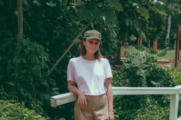 Nathalie Kelley in a garden wearing a cap and shorts