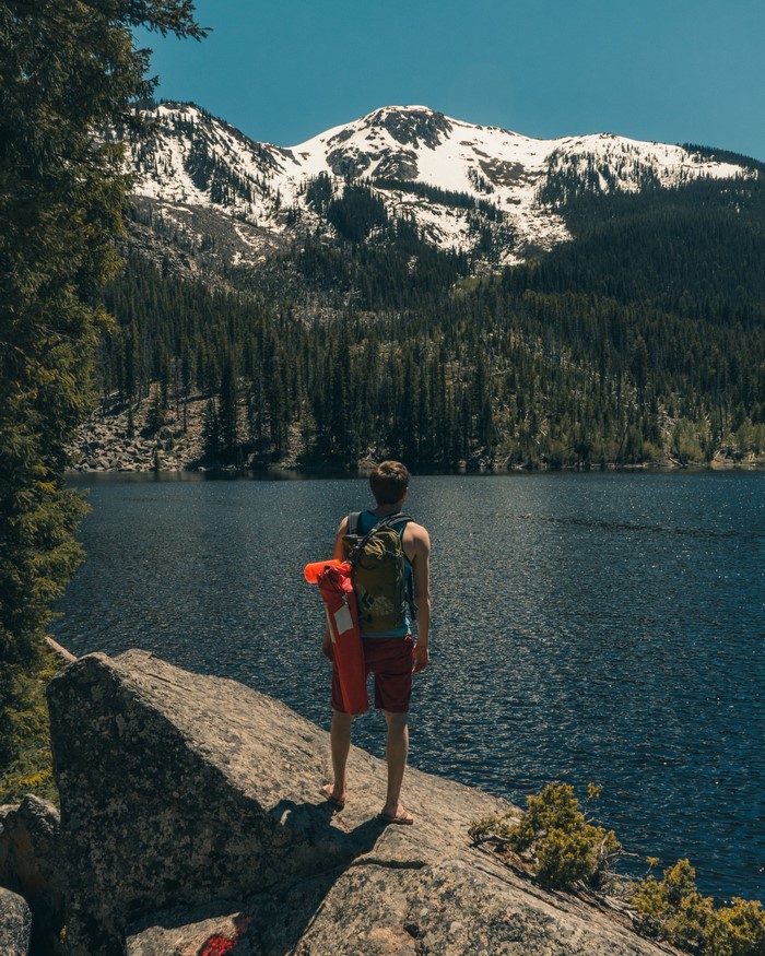 Man with backpack and sleeping bag by a mountain lake