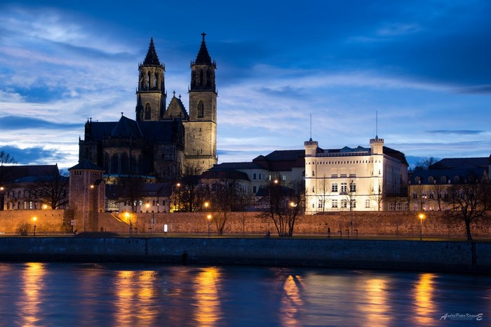 Magdeburg Cathedral and buildings reflected in the Elbe River at dusk