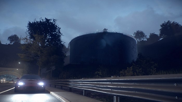 Red Toyota Supra driving on a road at night near a water tower