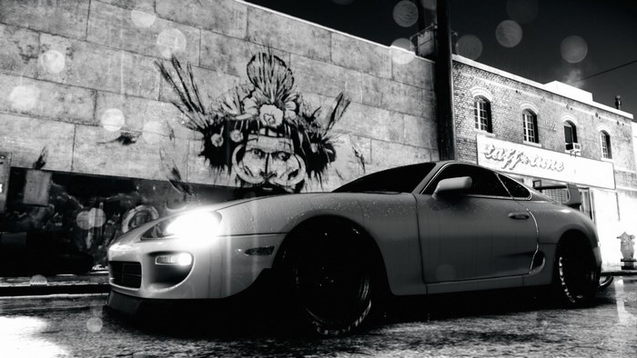 Toyota Supra parked in front of graffiti wall at night