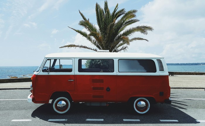 Red and white Volkswagen Type 2 van by the sea