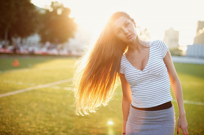 Woman with long hair on a sports field at sunset