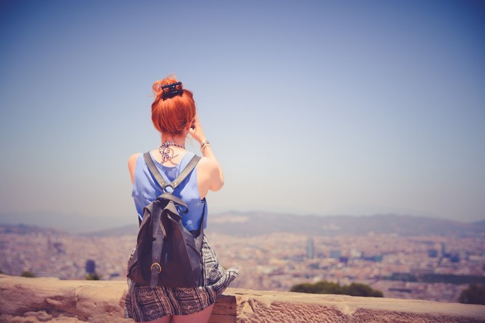 Woman with red hair taking a photo of a city