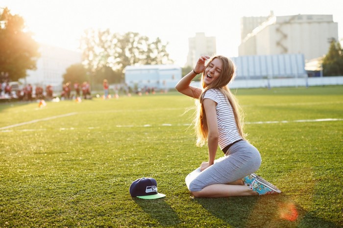 Woman in striped shirt and grey skirt on a sports field