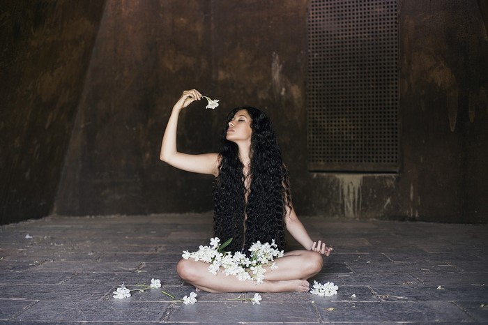 Woman with long dark hair holding a white flower
