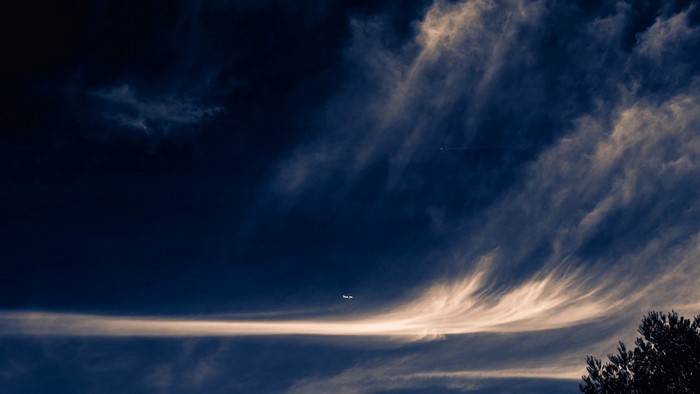Aircraft flying through clouds at dusk