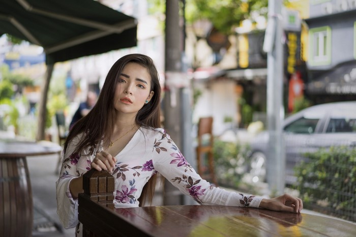 Asian woman in floral dress sitting at a table