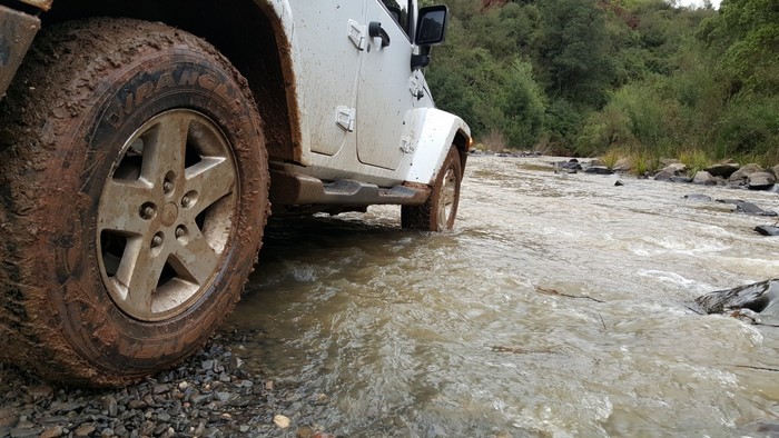 White Jeep Wrangler driving through a muddy river