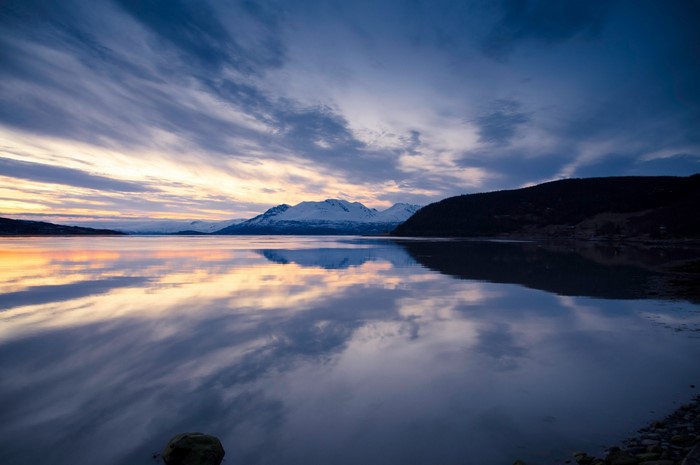 Snowy mountains reflected in a calm lake at sunset