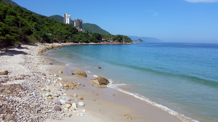 Rocky beach with turquoise ocean and green hills