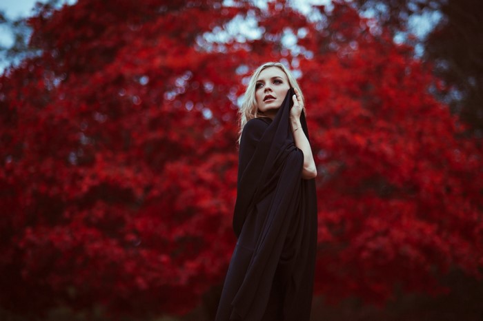 Woman in black dress with red tree background