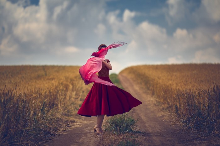 Woman in red dress with pink scarf in a wheat field
