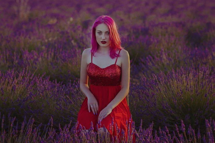 Woman with pink hair in a red dress in a lavender field