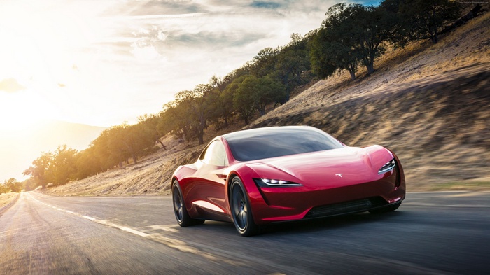 Red Tesla Roadster driving on a road