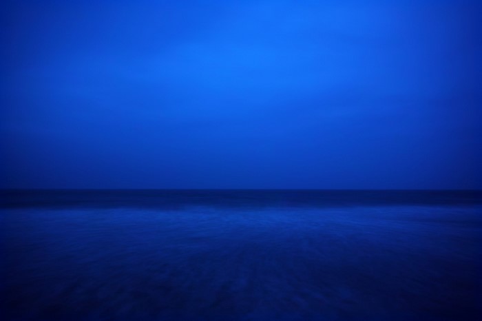 Blue ocean horizon at dusk with blurred waves