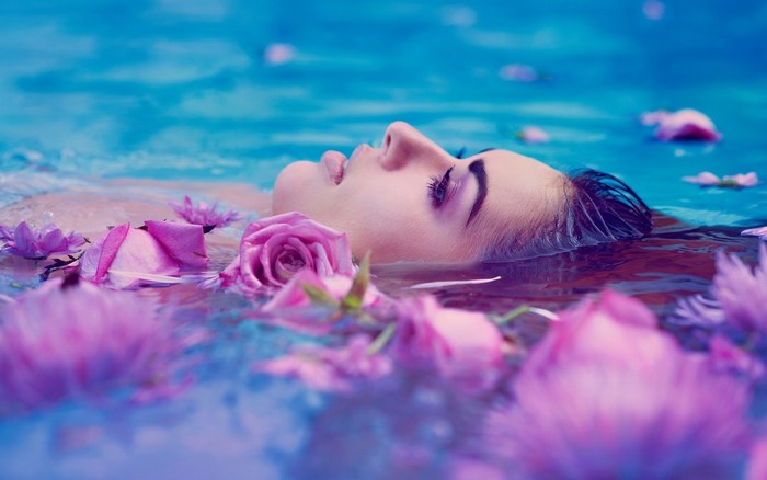 Woman floating in water with pink flowers