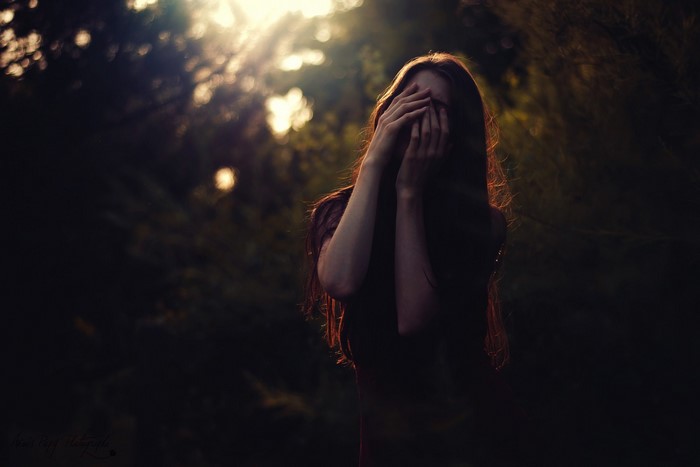 Woman with hands over face in sunlight