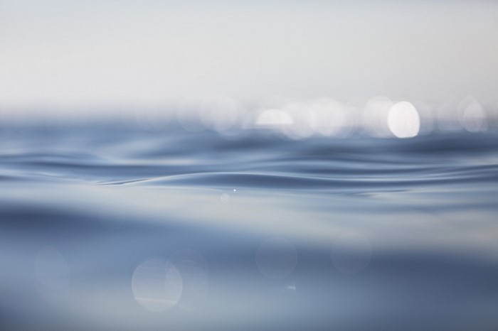 Close-up of gentle ocean waves with bokeh light reflections