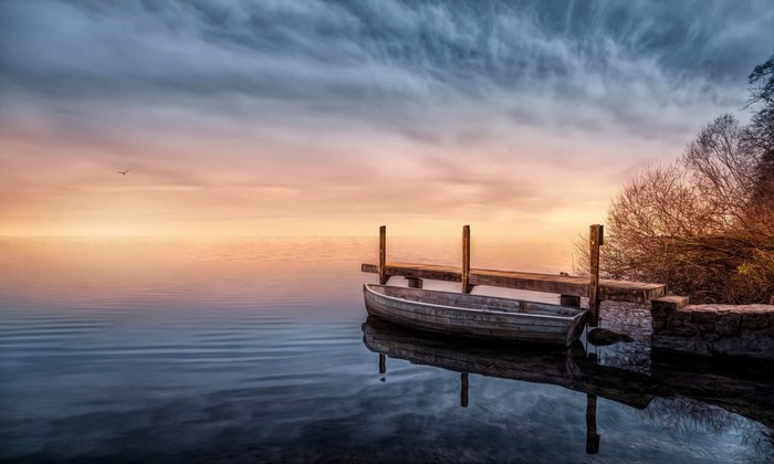 Boat docked at a pier during sunset over a calm lake