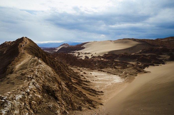 People hiking on a mountain ridge in a desert valley