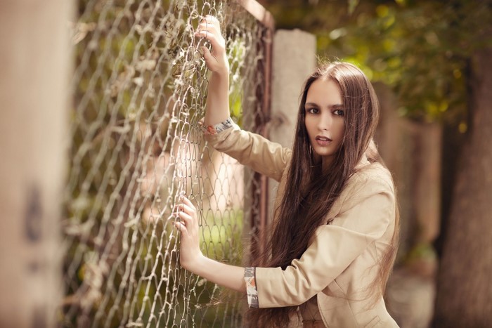 Woman leaning on a chain-link fence