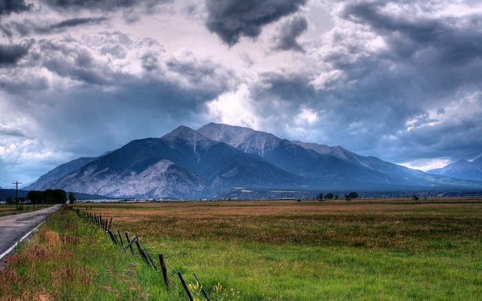 Stormy clouds over mountains and a field