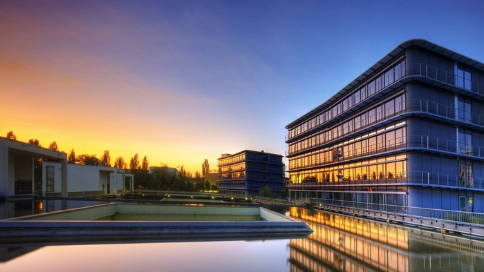 Modern office buildings reflecting sunset over water