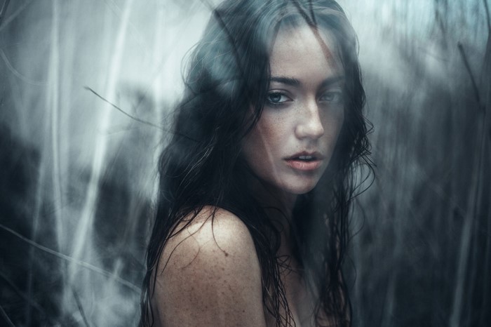 Woman with dark hair and freckles looking at camera