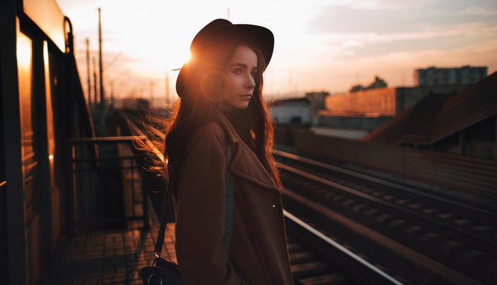Woman in hat at train station during sunset
