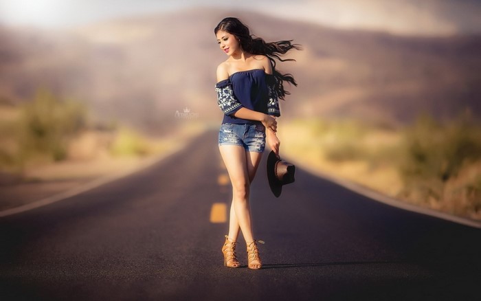 Woman in off-the-shoulder top and jean shorts on a road