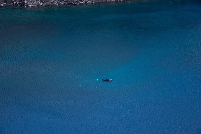 Boat on a vast blue ocean near rocky shore