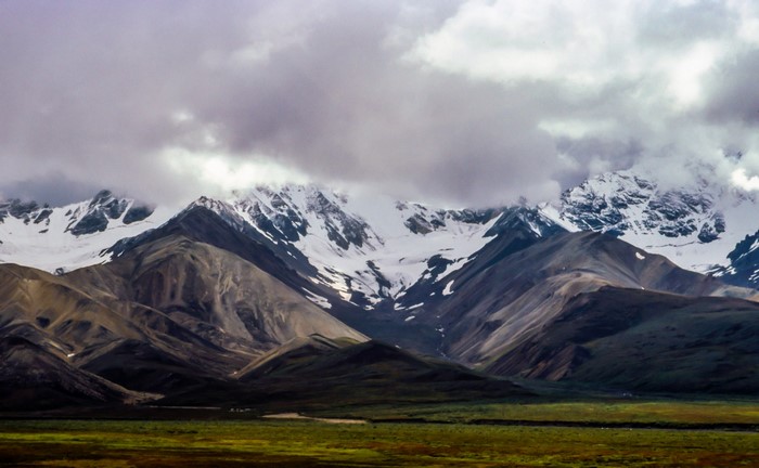 Snow-capped mountains under cloudy sky
